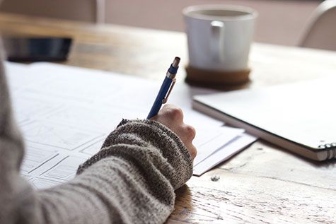 Someone writing their notes while having coffee 